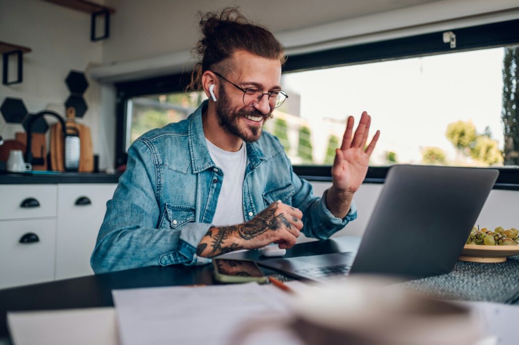 Young man working at home with laptop having a video call with colleagues